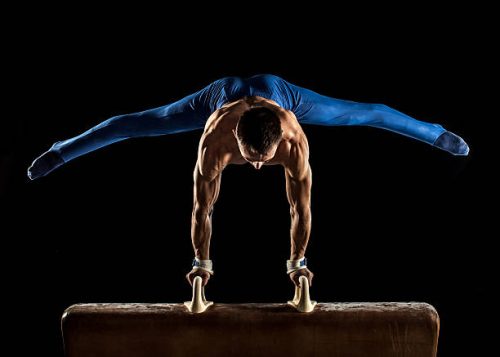 Male Gymnast doing handstand on Pommel Horse